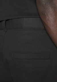 Svarta denimbyxor med en texturerad finish, som har en rektangulär bakficka och en Calvin Klein-logga på midjan.