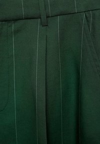 Tissu vert foncé avec de fines rayures blanches verticales, avec une ceinture, une boucle et une couture de poche latérale.