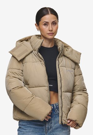 Beige Pufferjacke mit Kapuze, oversized Kragen, Reißverschluss und elastischen Bündchen. Hergestellt aus gestepptem Stoff mit glatter Textur.