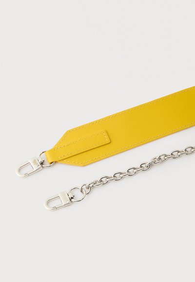 Sangle en cuir jaune reliée à une chaîne en argent avec des fermoirs métalliques sur fond blanc.