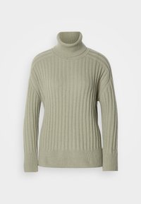 Vihreä turtleneck-paita, joka on valmistettu ribbikangasta. Pudotetut olkapäät, minimaalinen sauman yksityiskohtaisuus ja pitkät hihat.