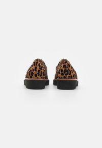 Leopardmønstret loafers med en brun mockaskinnøvre, svarte detaljer og en flat svart såle. Designet med en rund tå og lav hæl.