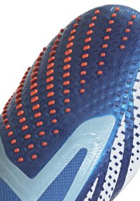 Blå idrottssko sula med texturerad yta och orangea gummistötte; släta silverdetaljer och blåa detaljer längs sidan.