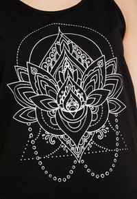 Débardeur noir avec un design détaillé de fleur de lotus blanche, entouré de motifs complexes et d'accents circulaires.