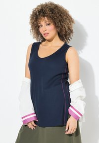 Marineblauwe mouwloze top met een V-hals, voorzien van roze zijnaadstiksels. Gepaard met een witte bloes met roze en paarse gestreepte manchetten.