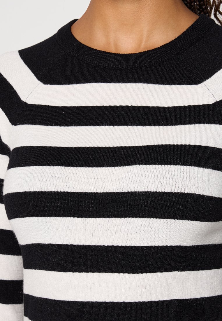 Pull à rayures noir et blanc avec un col rond, texture côtelée et matière en tricot de poids moyen, mettant en valeur des rayures horizontales.
