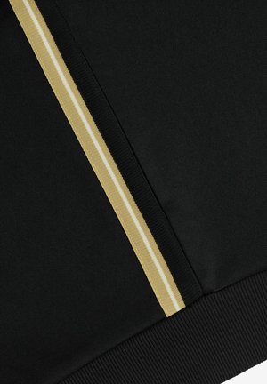 Tessuto nero con bordo verticale a righe beige e bianche e dettaglio orlo a costine lungo il bordo inferiore.