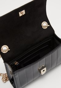 Borsa a tracolla nera in ecopelle con design trapuntato, hardware dorato, chiusura magnetica e interno in suede con scomparti per carte e tasca con zip.