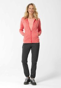 Felpa con zip color corallo e cerniera a contrasto, due tasche frontali, abbinata a pantaloni scuri a gamba affusolata e scarpe da atletica nere.