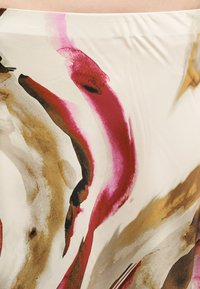 Κοντινό πλάνο αφηρημένου υφάσματος με ρευστές πινελιές σε κόκκινο, καφέ, μπεζ και μαύρο σε κρεμ φόντο.