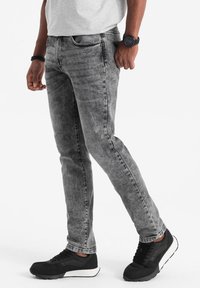 Harmaat slim-fit farkut, joissa on haalistunut pesu, puuvillasekoitekangas ja neljän taskun suunnittelu. Yhdistetty mustien urheilukenkiä kanssa.