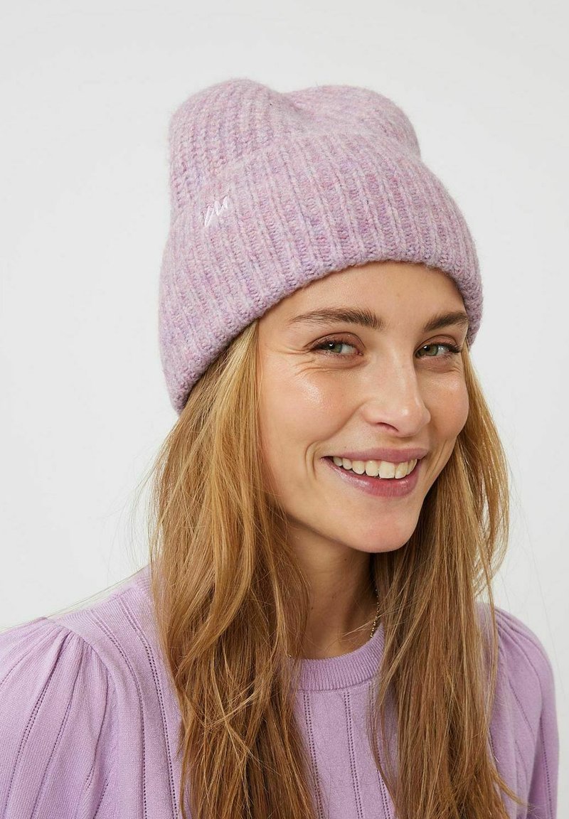 Gorro de punto rosa claro con textura acanalada y puño doblado. Presenta motas sutiles y un pequeño logo bordado en la parte delantera.