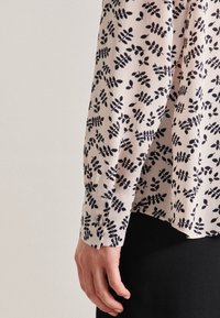 Långärmad skjorta i ljusrosa tyg med ett mörkt blommönster, med knappade cuffs och en avslappnad passform, lämplig för avslappnad klädsel.