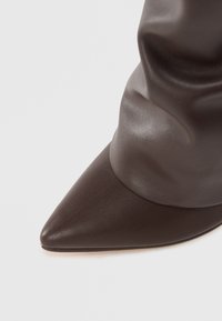 Bottine en cuir marron, à bout pointu, avec un dessus texturé et flou, et une finition lisse, présentant une silhouette élégante et un design à bout étroit.