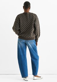 Brown, textured sweater with white polka dots, oversized fit, ribbed cuffs and hem paired with loose blue jeans and silver ballet flats.