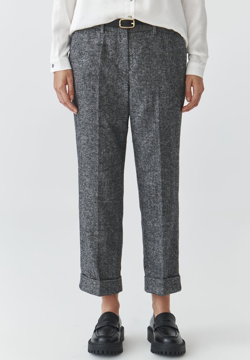 Gray wool trousers with a textured finish, featuring a rolled cuff, front pleats, and a black belt with a gold buckle. Paired with black shoes.