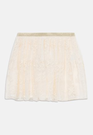 Jupe en dentelle crème claire avec un design superposé et une taille élastique dorée pailletée. Motifs floraux délicats sur tout le tissu.
