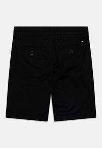 Schwarze Shorts aus glattem Stoff mit klassischem Design, zwei Gesäßtaschen mit Knopfverschlüssen und gestickten Details.