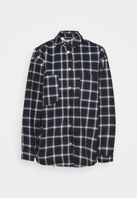 Svart och vit rutigt långärmad skjorta med krage, knappstängning fram och två bröstfickor, samt liggande platt på en vit bakgrund.