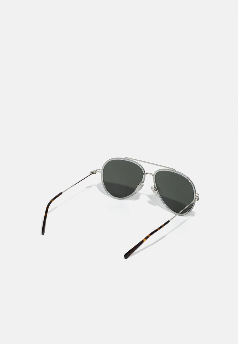 Des lunettes de soleil de style aviateur avec des verres gris foncé, une monture transparente et des branches en écaille de tortue. Des accents en métal léger rehaussent le design.