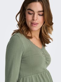 Light green ribbed dress with a v-neck and lace trim. Features gathered detail at the bust and a flared skirt. Soft fabric texture.