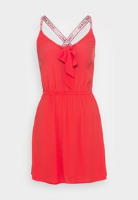 Punainen hihaton mekko, jossa on vyötäröllä solmittava nauha, V-pääntie ja logotunnuksilla varustetut säädettävät olkaimet. Sileä kangas ja polvenpituinen muotoilu.