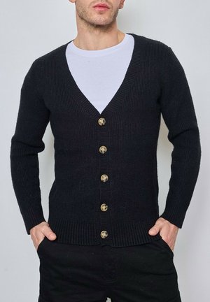 Gilet en tricot noir avec un décolleté en V profond, présentant six boutons dorés et des finitions côtelées sur les poignets et l'ourlet.