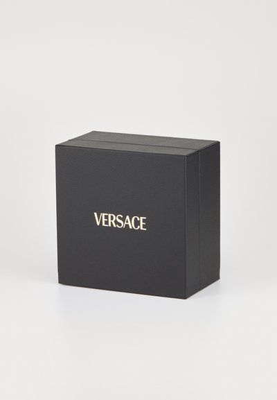 Juodas stačiakampis dėžutė su tekstūruotu paviršiumi, priekyje su auksiniu "VERSACE" logotipu. Uždara, minimalistinė dizaino forma.