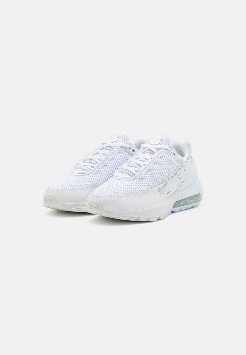 Ett par vita Nike Air Max sneakers med nätöverdelar, synlig luftkuddar i sulorna och subtila silverfärgade Nike swoosh-logotyper.