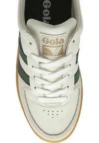 Deportiva de cuero blanco con franjas verdes, suela de goma, punta redonda, cierre de cordones y etiqueta de la lengua con la marca "Gola" en impresión dorada.