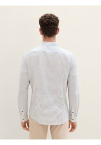 Lichtblauw shirt met lange mouwen en een subtiel gestreept patroon, met een button-down kraag en contrasterende knoopaccenten op de manchetten en voorpijp.