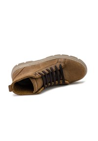 Botín de ante marrón con cordones negros, un interior acolchado, panel lateral texturizado y una suela de goma gruesa para mayor amortiguación y soporte.