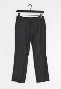 Černé kalhoty vystavené, s rovnými nohavicemi, jemně strukturovaným vzorem a zapínáním na knoflíky, zavěšené na černém ramínku.