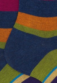 Due calzini a maglia colorati sovrapposti, con strisce in navy, arancione, verde, rosa, blu, beige e viola.