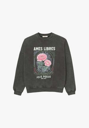 Sweat-shirt gris foncé avec motif floral rose encadré de vignes décoratives et texte blanc "AMES LIBRES" et "JOLIE POÉSIE DEPUIS 1975" sur le devant.