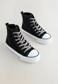 Mustad kõrge säärega lõuendjalatsid valgete kummist varbakorkidega, millel on leopardimustrilised paelad ja küljele kinnituv lukk.