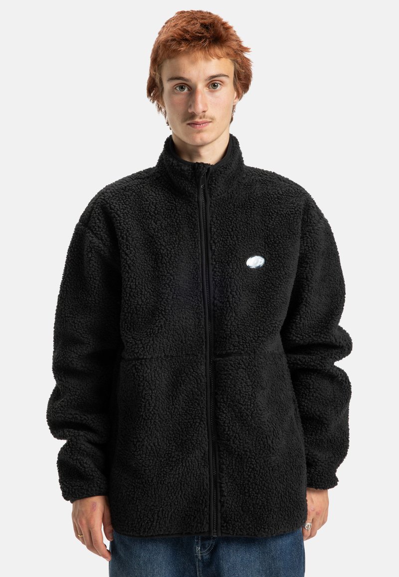 Zwarte fleecejack met een hoge kraag, ritssluiting en textuurstof. Heeft een klein logo-opdruk op de linkerborst.