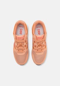 Paire de chaussures de course ASICS couleur pêche avec lacets, bouts en mesh, et col rembourré, vues de dessus sur un fond blanc.
