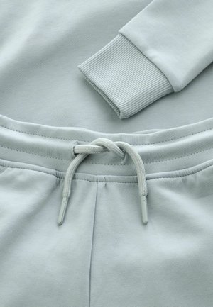 Hanorac și pantaloni de trening gri deschis, cu mansete ribbate și talie elastică dotată cu șnur. Textură de țesătur�ă moale.