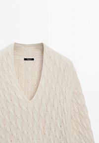 Pull en maille torsadée crème à col en V avec un motif texturé et un col côtelé, étiqueté Massimo Dutti.