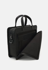 Mallette en cuir noir avec doubles poignées, surface texturée, fermeture éclair et deux compartiments intérieurs pour l'organisation. Doublure noire lisse.