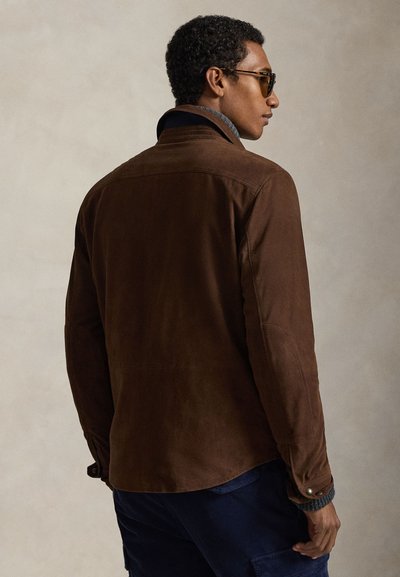 Καφέ τζάκετ από σουέντ με άνετη εφαρμογή, που διαθέτει μανσέτα με κουμπιά και απαλό γιακά. Διακριτές ραφές και υφή στο ύφασμα το καθιστούν ιδανικό για casual εμφάνιση.