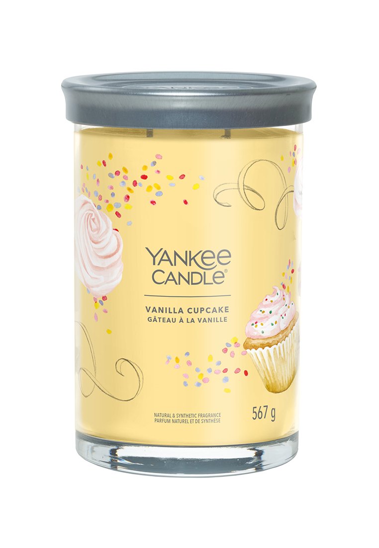 Bougie Yankee Candle dans un pot en verre transparent avec un couvercle en métal gris. Étiquette jaune avec un glaçage rose, des paillettes, et le texte "Muffin à la Vanille". 567 g.