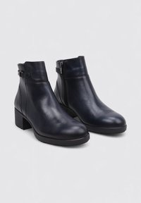 Botas de cuero hasta el tobillo en azul marino, con cremallera lateral, tacón cuadrado y un acabado suave con un detalle de correa en el tobillo.