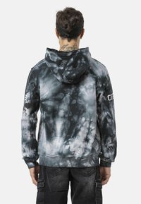 Zwarte en grijze tie-dye hoodie. Voorzien van geribbelde manchetten en zoom, gestructureerde stof en zijlogo's op de mouwen.