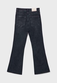 Jean en denim noir foncé lavé, vu de dos, avec deux poches arrière, une taille haute, des jambes évasées et des ourlets bruts.