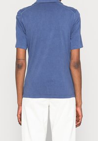 Camisa polo de algodón azul con mangas cortas, un cuello y un diseño simple. Equipado con un dobladillo recto y una textura suave.