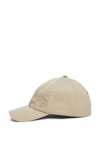 Cappellino da baseball beige con visiera curva, realizzato in tessuto testurizzato. Presenta un accento con logo dorato sul pannello frontale e dettagli di cucitura.