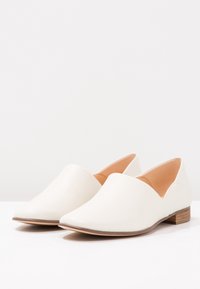 Bottines blanches en cuir à enfiler avec un bout pointu et un petit talon en bois. Texture lisse et design minimaliste sans éléments décoratifs.