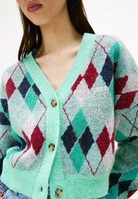 Cardigan verde menta con un motivo a diamante in rosso, blu navy e teal. Presenta un collo a V, chiusura con bottoni e una texture lavorata a maglia.